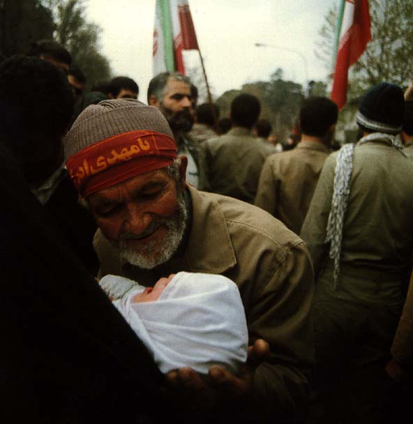 Доброволец прошяется с внуком, уходя на фронт. На повязке написано: Махди, дай мне сил.